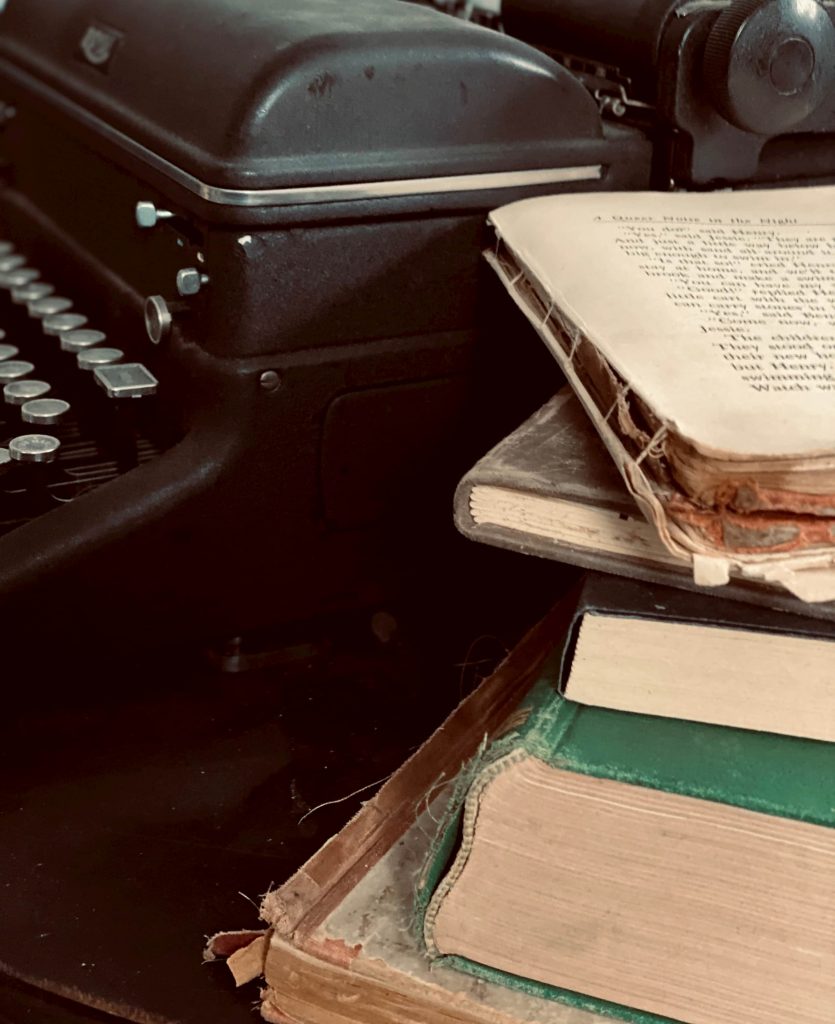 books on a desk with a typewriter